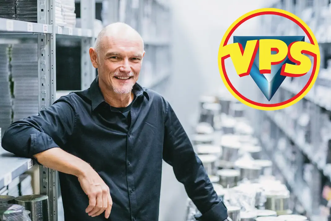 CEO Andreas Kirchen vor den Lagerregalen von VPS Film, umgeben von DVDs und Medienprodukten.